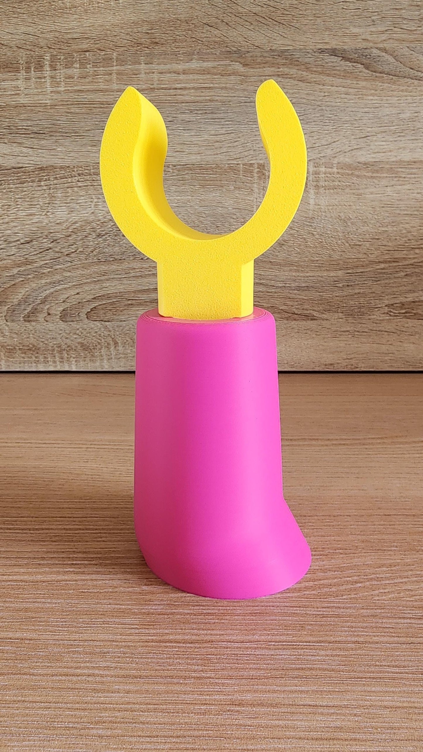Pink and yellow Minifig-Inspired Headphone Holder on rustic wood surface