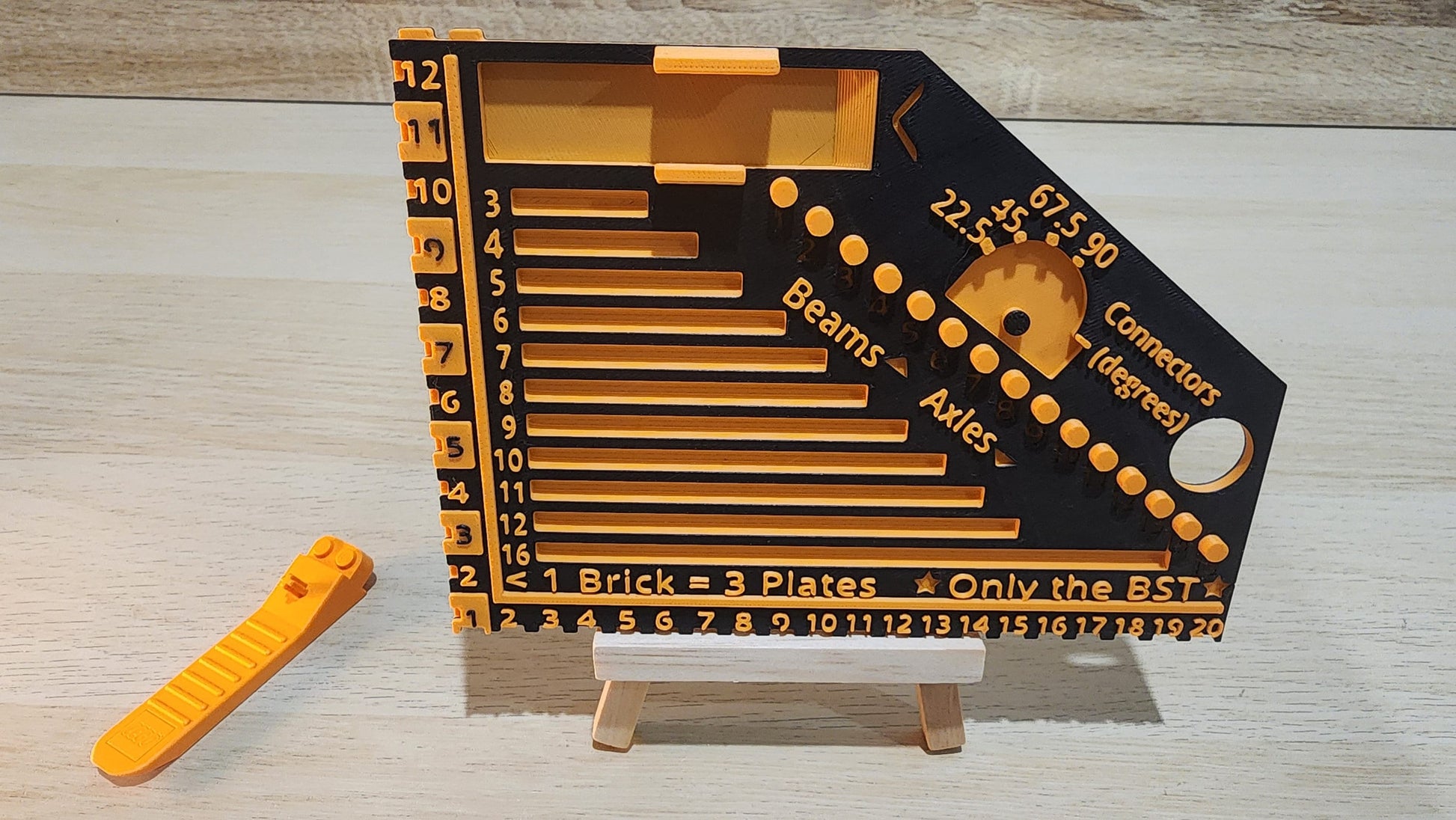 Black and orange brick ruler with a brick separator next to it.