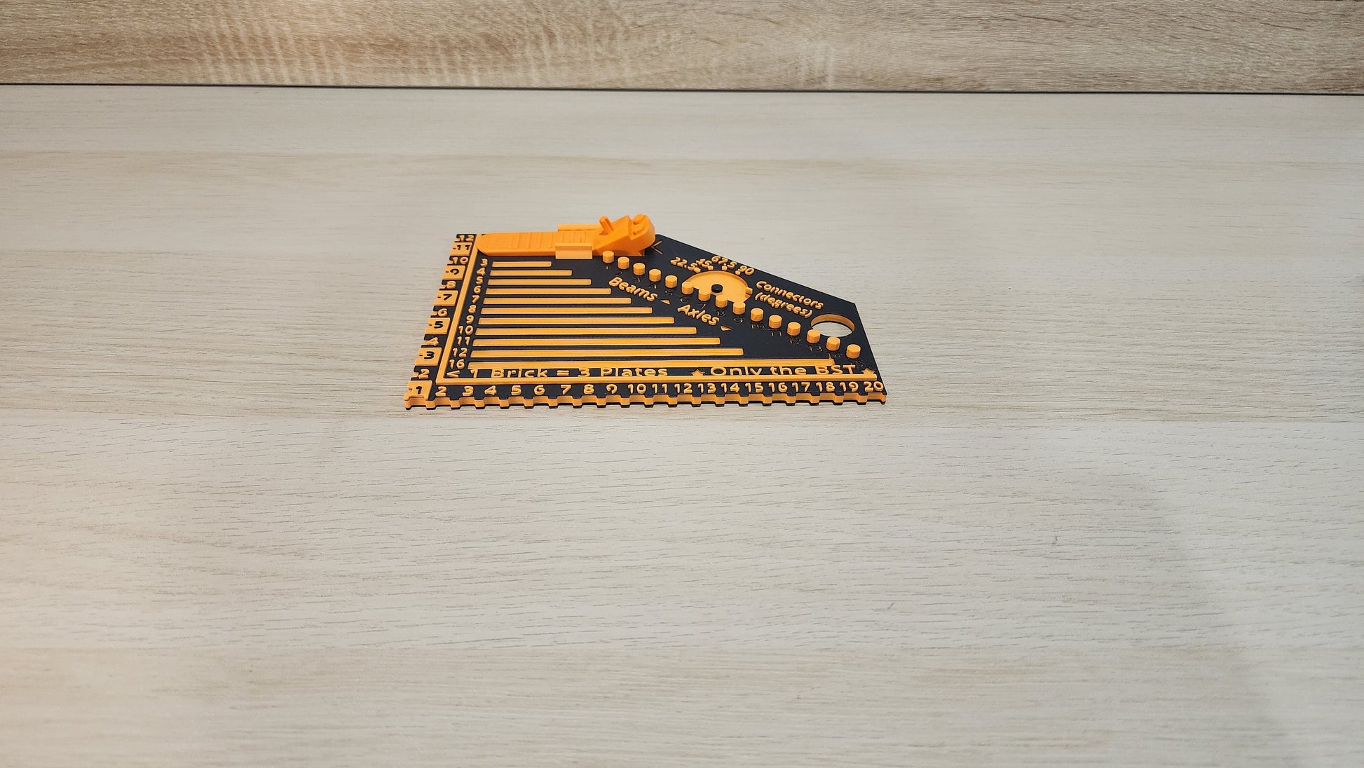 Black and orange brick ruler with a brick separator attached showing the side view.