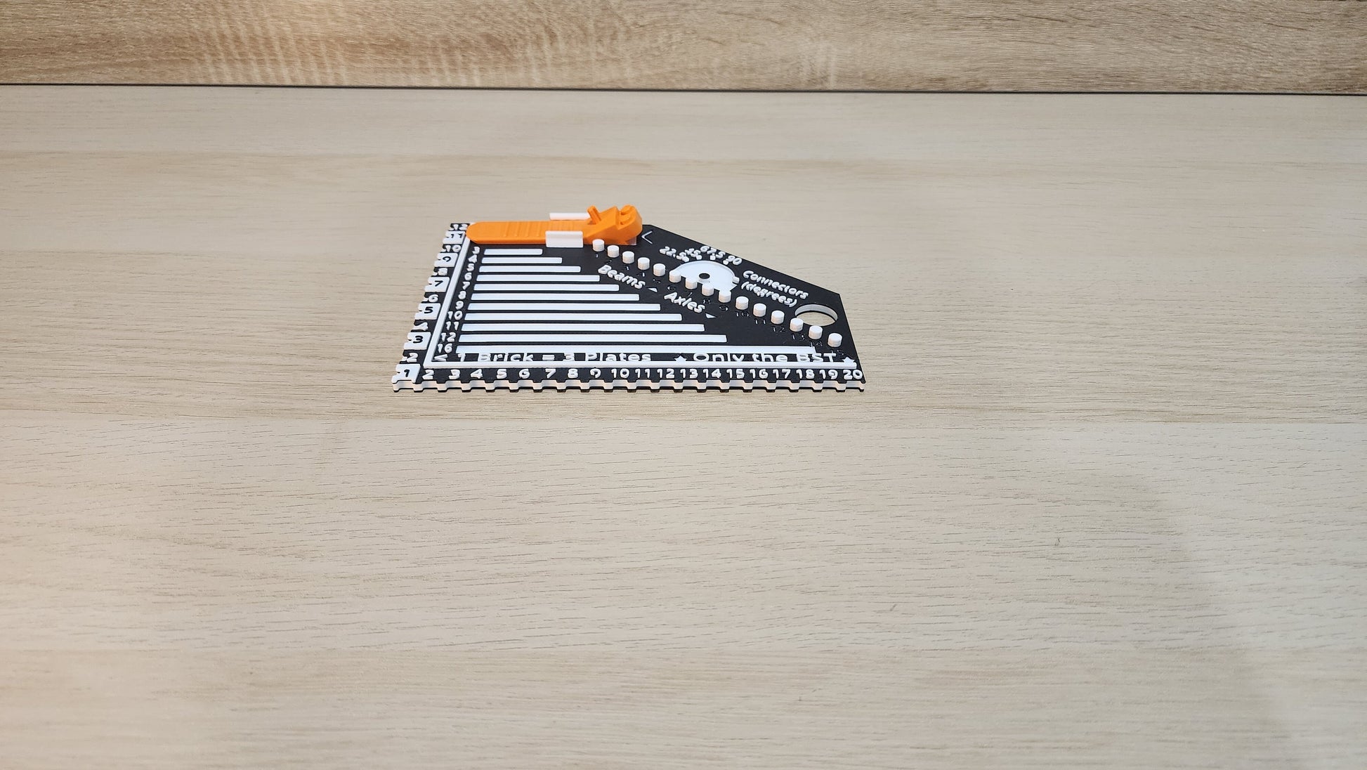 Black and White brick ruler with a brick separator attached showing the side view.