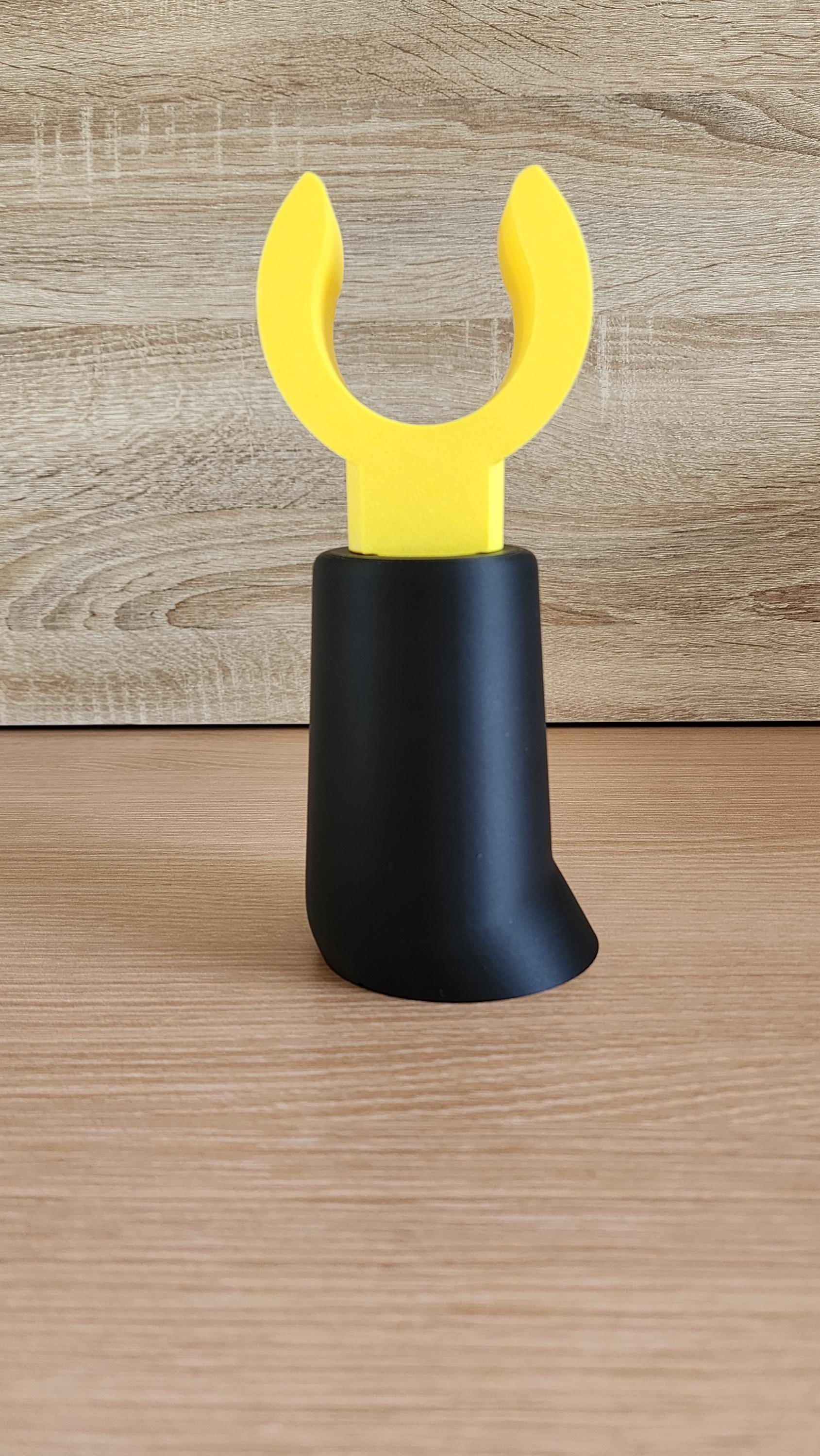 Black Minifig-Inspired Headphone Holder with yellow claw hand on wood background