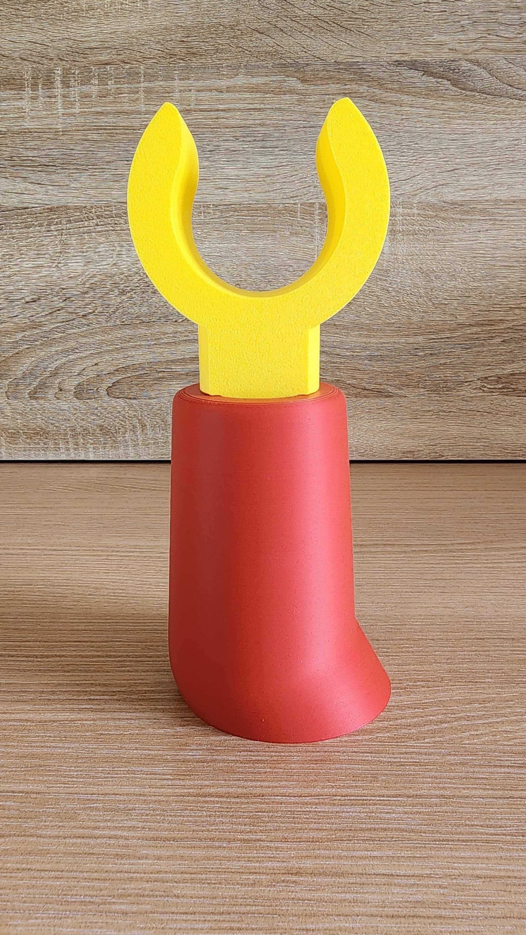 Red and yellow Minifig-Inspired Headphone Holder in upright position on wood background